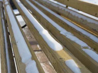 Sarı ahşap bankta kar var..