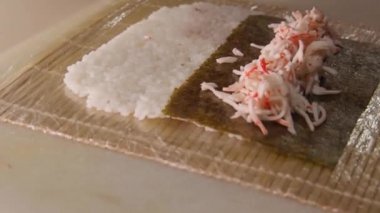 Salatalık ve avokadoyla Japon dürümü yapma sürecinin yakın çekimleri.