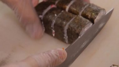 Japon rulolarını Norveç yosunlarıyla kesme işlemi beyaz bir adamın elleriyle eldivenli..