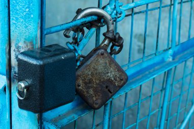 Mavi bir kafese asılmış iki büyük metal kilit..