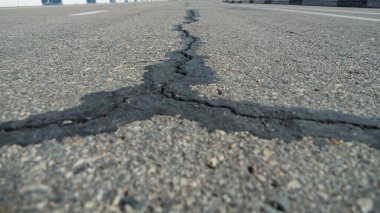 Asfalttaki büyük siyah bir çatlak üç yönde ayrılır..