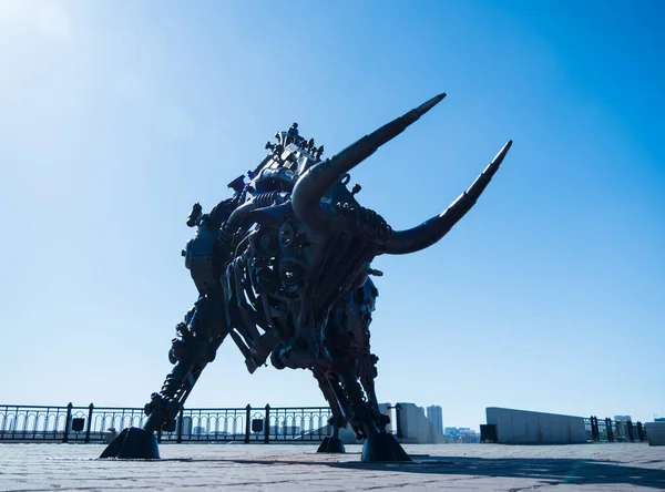 A metal statue of a bull made of gears and details of mechanisms.