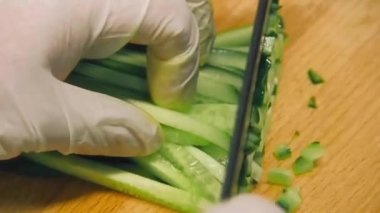 Beyaz eldivenli bir aşçı havuç ve salatalığı doğruyor ve tavada yumurta ve pirinçle kızartıyor..