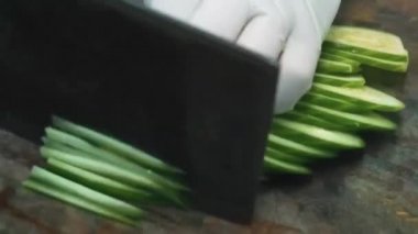 Beyaz eldivenli bir aşçı havuç, salatalık, ahşap mantar ve cam erişteden salata yapar..