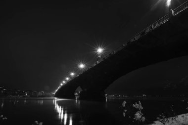 Kış. İyi geceler. Nehrin üzerindeki köprü. Fener ışıkları buzda yansır. 