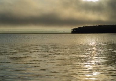 Doğu Sibirya. Baykal bölgesi. Yaz. Sis. Kasvetli gün doğumu. Göl. Suyun üzerinde parla.