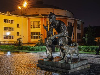 Doğu Sibirya. Irkutsk şehri. Yağmur. Sirkin yakınındaki ünlü film yönetmeni Leonid Gaidai 'nin anıtı. Filmin karakteri. Ağzında bir paket dinamit tutan bir köpek..