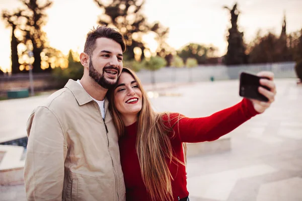 Erkek ve kız gün batımında selfie çekiyorlar, yaşam tarzı konsepti.