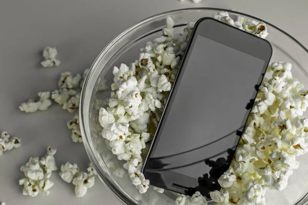 Popcorn and telephone in a bowl on a white background, in a zenithal plane.