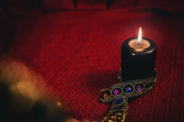 Černá svíčka ozářená drahokamy zdobenými na červené látce, esoterický koncept — Stock fotografie