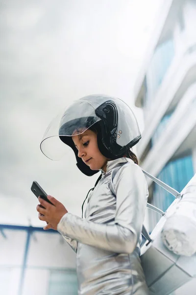 Teknoloji konsepti, kız akıllı telefonunu sokaktaki fütüristik bir binadan alıyor.
