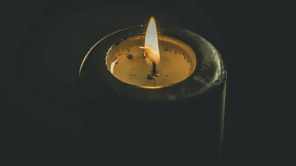 a black candle lit on a black background, esoteric concept