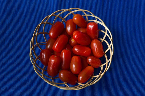 Fresh tomatoes in a basket on a blue background — Stock Photo, Image