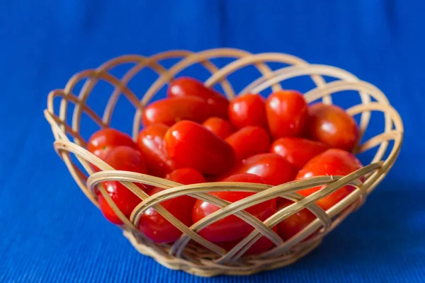 Fresh tomatoes in a basket on a blue background — Stock Photo, Image