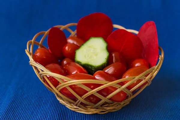 Fresh tomatoes with cucumber in a basket on a blue background — Stock Photo, Image