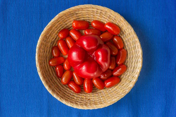 Ferske tomater med rød paprika i en kurv på blå bunn – stockfoto