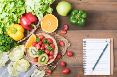 defter üzerinde tahta arka plan ile meyve ve sebze