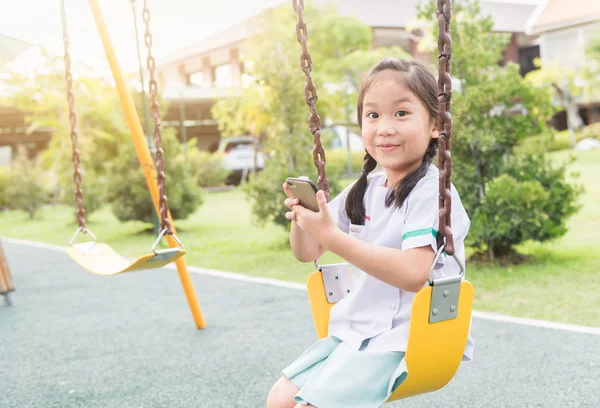 Cute girl show smart phone nel parco giochi per bambini — Foto Stock
