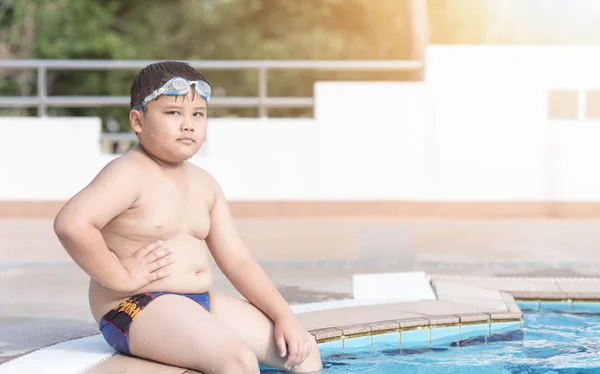 Zwaarlijvige jongen zitten in zwembad — Stockfoto