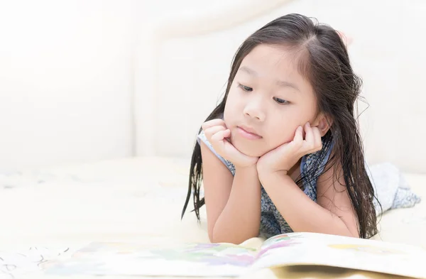 Χαριτωμένο μικρό ασιατικό κορίτσι στο Νυχτικό διαβάζοντας ένα βιβλίο. — Φωτογραφία Αρχείου