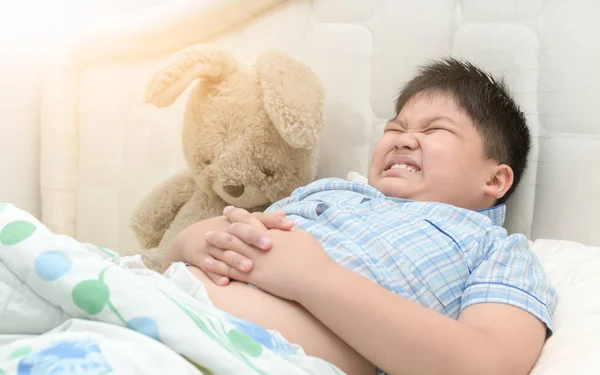 Niño obeso en su cama tiene dolor de estómago — Foto de Stock