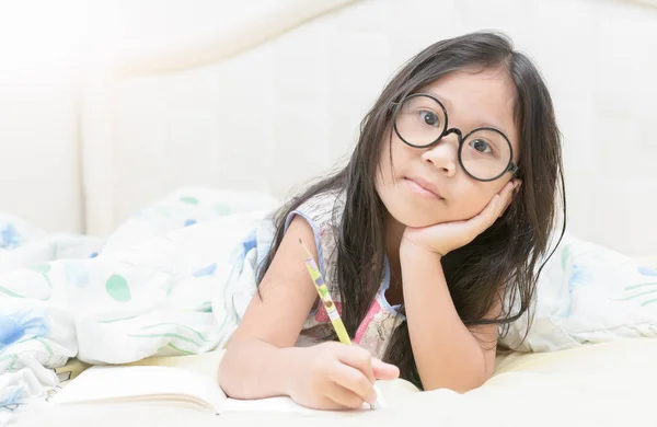 Asiatisk tjej skriver till dagbok på sängen — Stockfoto