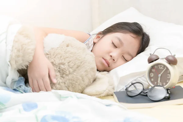 Süße kleine asiatische Mädchen schlafen und umarmen Teddybär auf Bett — Stockfoto