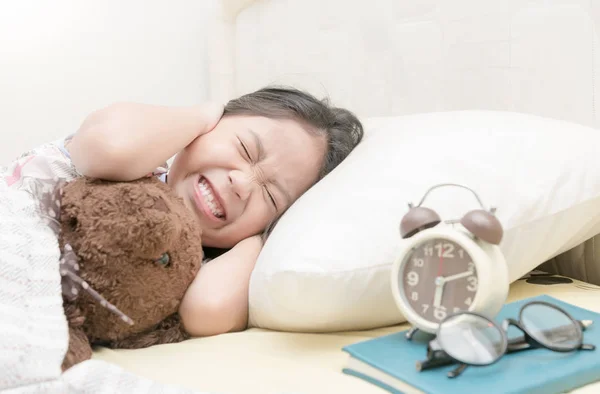 Annoyed girl being awakened by an alarm clock — Stock Photo, Image