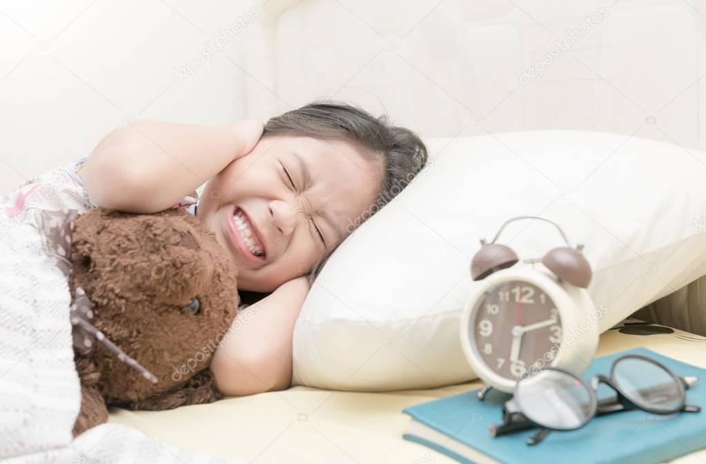 Annoyed girl being awakened by an alarm clock