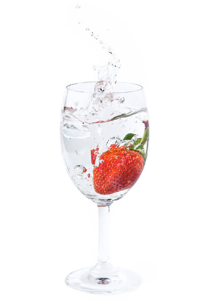 fresh strawberry dropped into water in wine glass with splash 