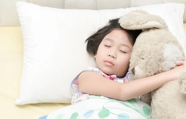 Милая маленькая азиатская девочка спит и обнимает плюшевого мишку на кровати — стоковое фото