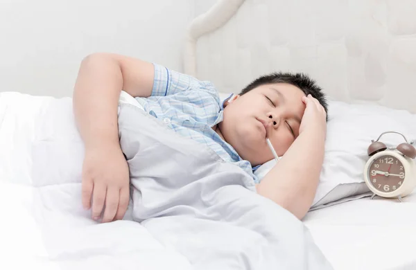 Niño enfermo con termómetro acostado en la cama . — Foto de Stock