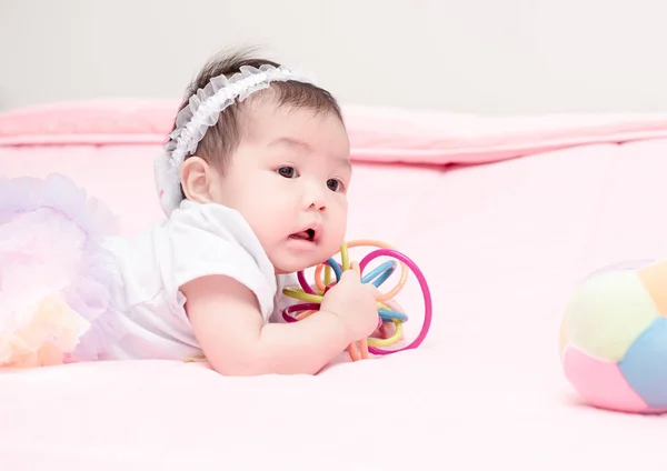 Aranyos baba mosolyog, és a játék játék rózsaszín takaró — Stock Fotó