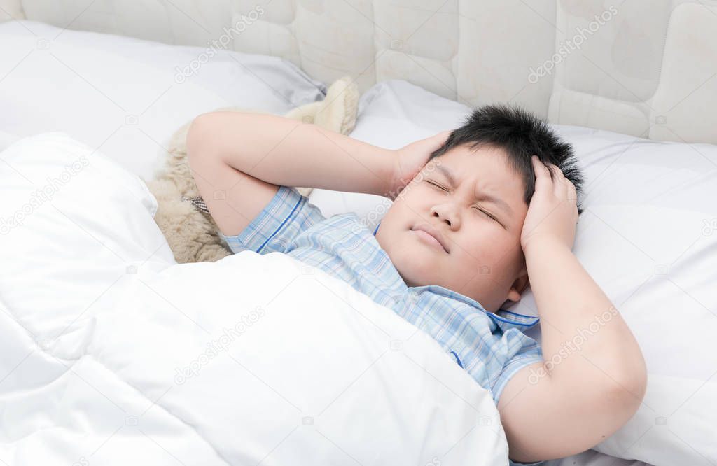 Child lying down suffering from a headache.