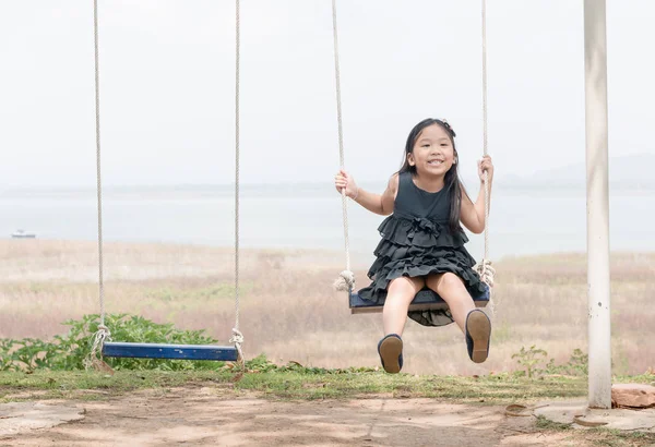 Aranyos lány játék swing ülés a természet háttér — Stock Fotó