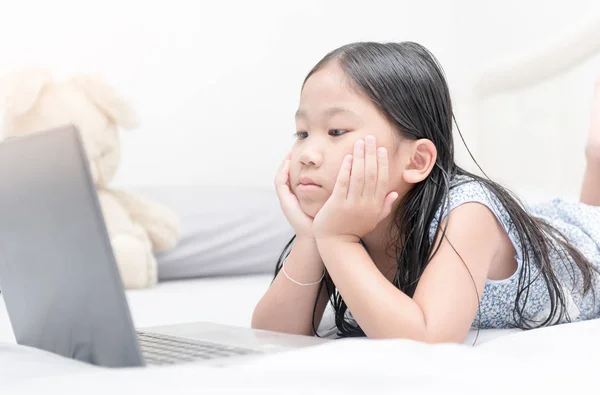 Carino asiatico ragazza cerca computer su letto , — Foto Stock