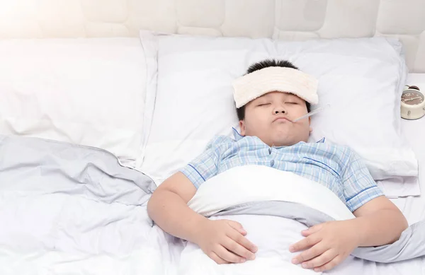 Больной мальчик с термометром лежит в постели . — стоковое фото