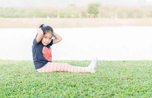 Bonito asiático menina exercício no verde grama — Fotografia de Stock