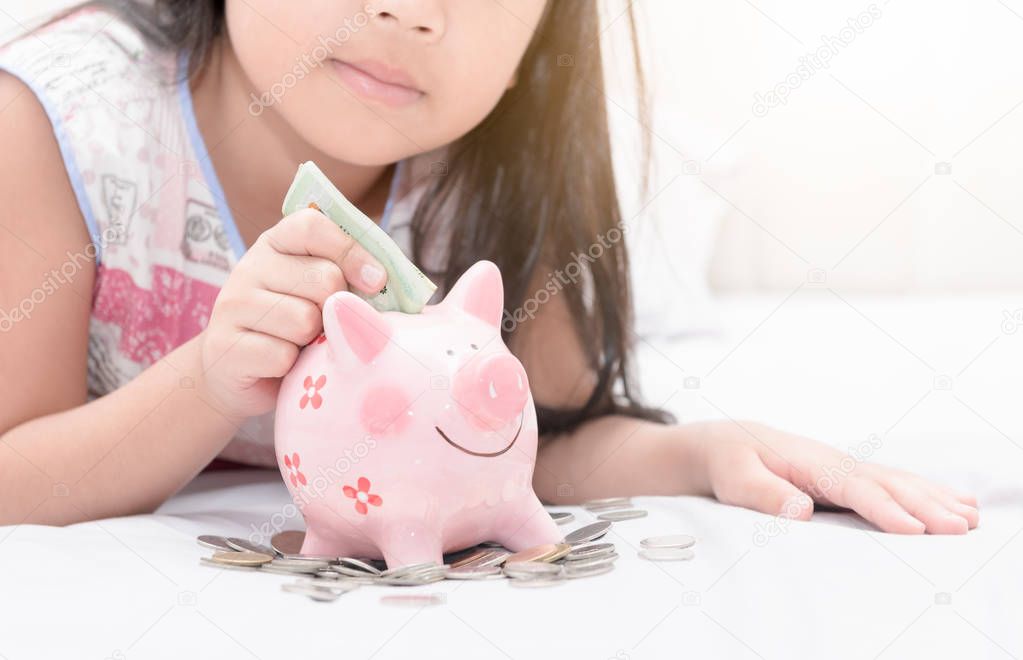 girl hand put money to piggybank on bedroom