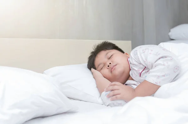 Толстый мальчик спит на кровати утром — стоковое фото