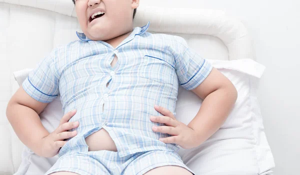 ベッドの上の肥満少年太りすぎて腹痛 — ストック写真