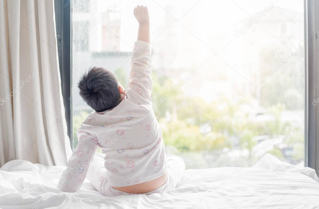 obese fat boy in pajamas is sitting on  bed