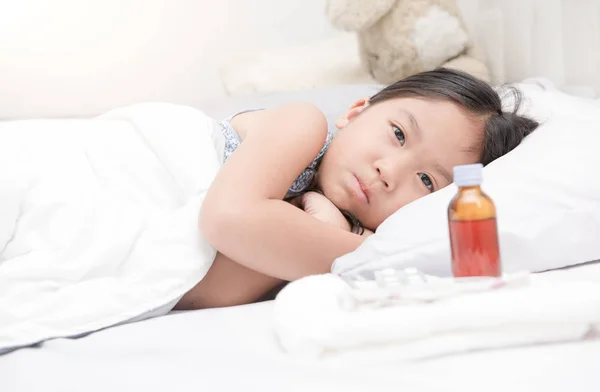 Больная девушка лежит в постели и лечит сироп — стоковое фото