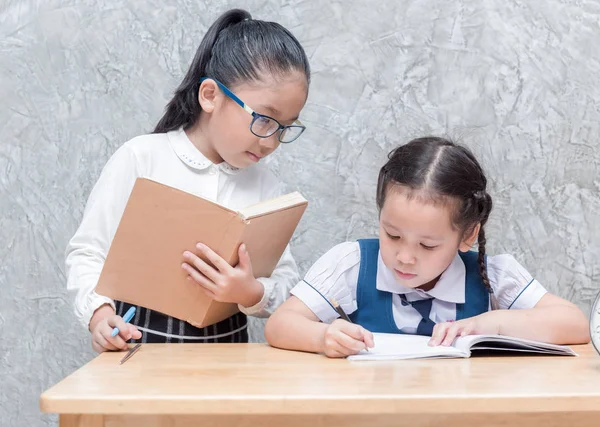 Little teacher looking student doing homework — Stock Photo, Image