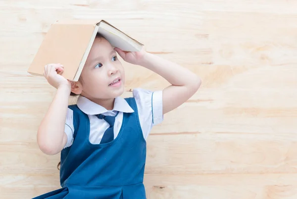 Asiática chica con libro en cabeza pensando en madera — Foto de Stock