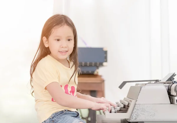 Χαριτωμένο μικρό κορίτσι πληκτρολογώντας σε ρετρό γραφομηχανή — Φωτογραφία Αρχείου