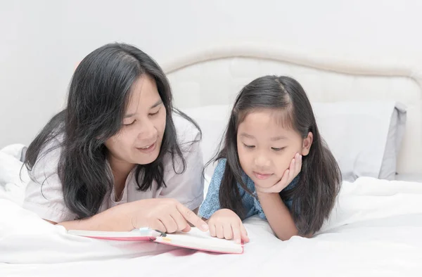 Anne ve kızı yatakta kitap okumak — Stok fotoğraf