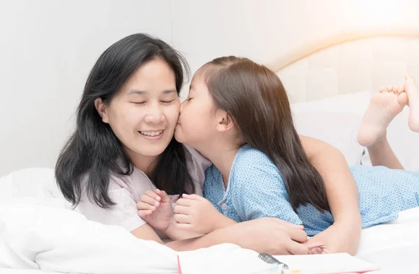 Niña está besando a su hermosa madre joven en la mejilla — Foto de Stock