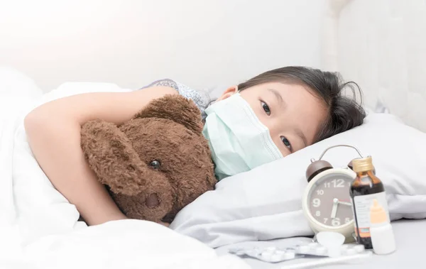 Chica enferma con máscara higiénica acostada en la cama — Foto de Stock
