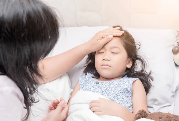 Mor mäta temperaturen på henne sjuk unge för hand. — Stockfoto